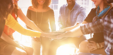 Group of happy colleagues forming hand stack in office