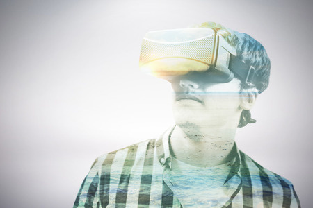 Young man wearing virtual reality glasses against serene beach landscapeの写真素材