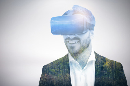 Happy young businessman using virtual reality glasses against autumn trees in forest