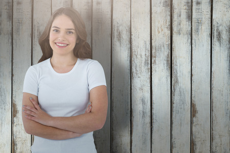 Portrait of confident model standing with arms crossed against wood backgroundの写真素材