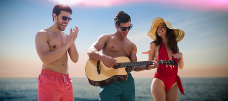 Friends playing music in swimwear against idyllic view of sea