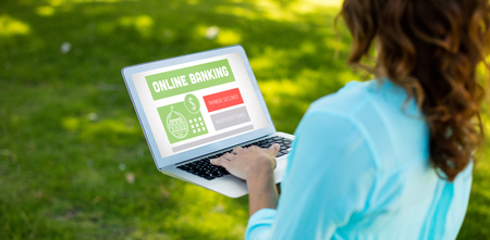 Online banking text on gray display against woman using laptop in parkの写真素材