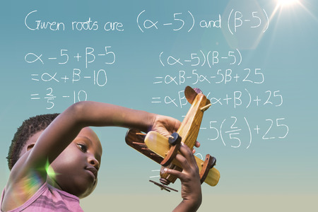 Playful boy holding toy airplane against blue skyの写真素材