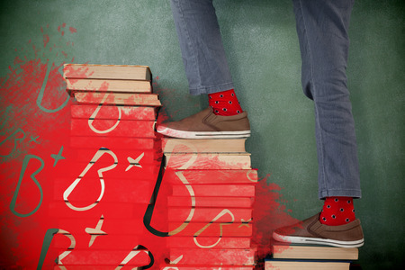 Graphic image of B plus grade against schoolboy climbing steps of books stack against chalkboardの写真素材