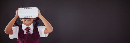 Schoolgirl using virtual reality headset against blackboard in classroomの写真素材