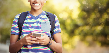 Portrait of schoolboy using mobile phone in campus at school