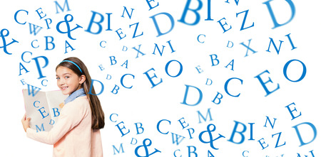 Portrait of smiling girl holding book against letters on a white backgroundの写真素材