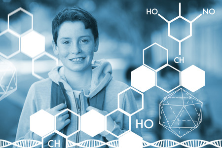 Graphic image of chemical structure against smiling schoolboy standing with schoolbag in campusの写真素材
