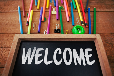 Welcome text against white background against chalkboard with colorful pencils on tableの写真素材