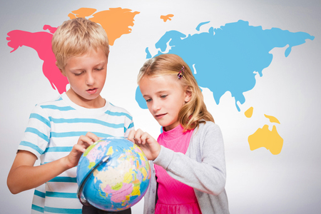 Friends looking at globe against grey backgroundの写真素材