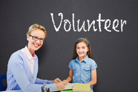 Portrait of teacher with student writing on book against black chalkboardの写真素材