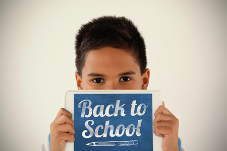 Back to school text over white background against schoolboy holding digital tablet against white backgroundの写真素材