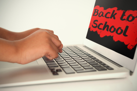 Back to school text on pink splash against schoolboy using laptopの写真素材