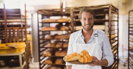 Digital composite of Happy small business owner man holding croissantsの写真素材
