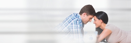 Digital composite of Couple lying on the floor with a piggy bankの写真素材