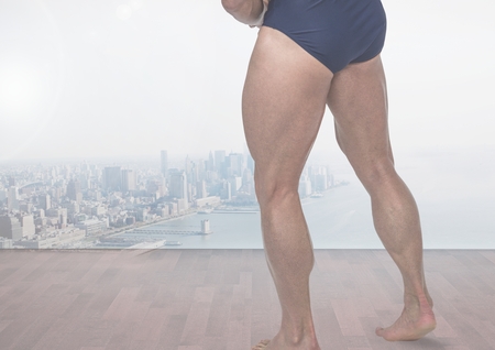 Digital composite of Strong man's muscular legs in front of cityの写真素材