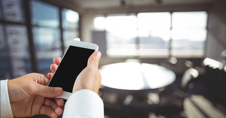 Digital composite of Business man using a phone against office backgroundの写真素材