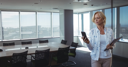 Digital composite of Business woman looking at a phone against office backgroundの写真素材
