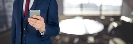 Digital composite of Business man using a phone against office backgroundの写真素材