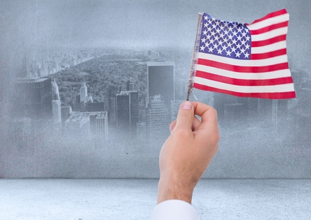 Digital composite of Hand holding American flag in cityの写真素材