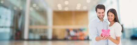 Digital composite of Happy couple holding a piggy bankの写真素材
