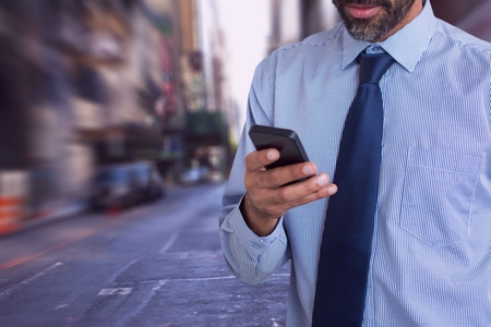 Digital composite of Business man looking at a phone against city backgroundの写真素材