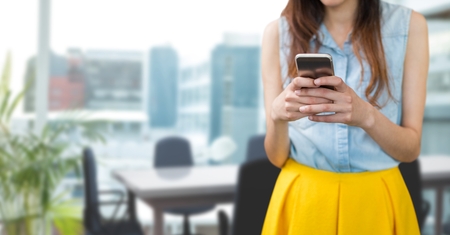 Digital composite of Business woman using a phone against office backgroundの写真素材