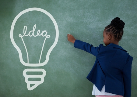 Digital composite of Office kid girl writing on a green wall with a bulb iconの写真素材