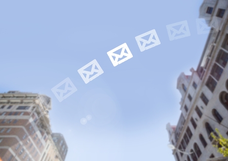 Digital composite of CEmail icons fading in city sky between buildingsの写真素材