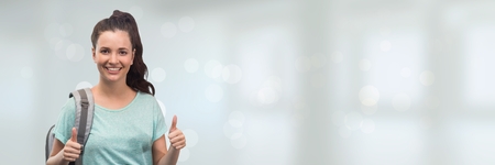 Digital composite of Happy young woman standing against wide blank with lightsの写真素材