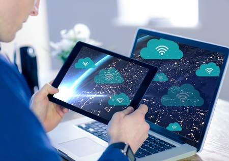 Digital composite of Holding tablet and Planet earth with icons of clouds and wifiの写真素材