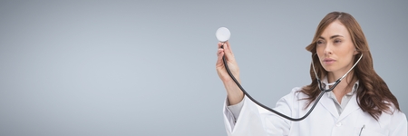 Digital composite of Doctor woman holding a stethoscope against grey backgroundの写真素材