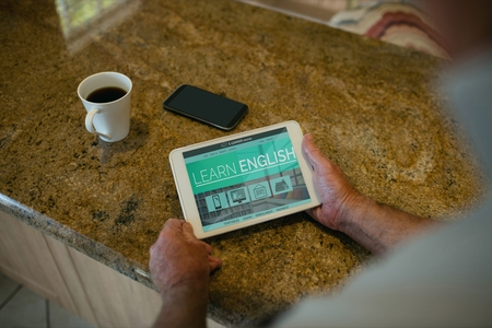 Digital composite of Man holding a tablet with e-learning information in the screen