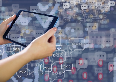 Digital composite of Holding tablet and Chat bubble icons over city