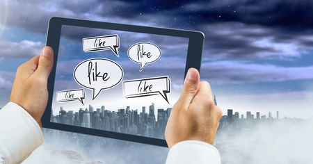 Digital composite of Holding tablet and Like chat bubbles over city