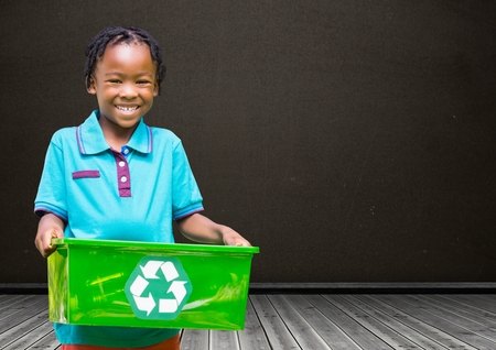 Digital composite of Boy holding recycling box in front of blackboardの写真素材