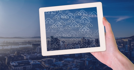 Digital composite of Holding tablet and City with cloud upload icons