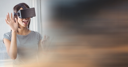 Digital composite of Business woman hands up in virtual reality headset and blurry sunset transitionの写真素材