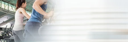 Digital composite of Man and woman on cross trainer with blurry white transition