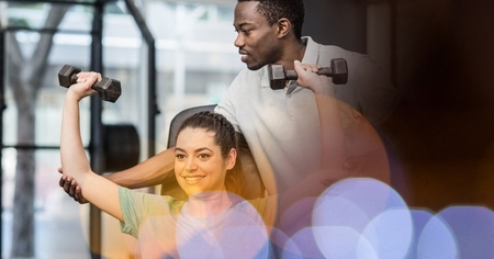 Digital composite of Instructor assisting woman in lifting weights at gymの写真素材