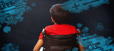 Rear view of boy sitting in wheelchair against black backgroundの写真素材