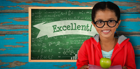 Happy girl holding books and apple against excellent! against green chalkboardの写真素材