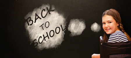 Girl sitting in wheelchair in school against blackboardの写真素材