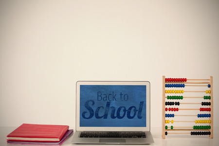 Back to school text over white background against books with laptop and abacus on tableの写真素材