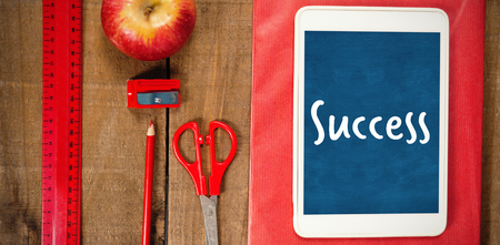 Success text against white background against overhead view of school supplies with digital tablet...