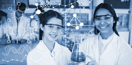 Illustration of chemical formulas against smiling schoolgirls doing a chemical experiment in...