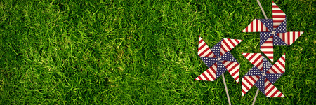 3D image of pinwheel toy with American flag pattern against full frame shot of grassy fieldの写真素材