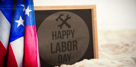 Happy labor day text with tools on red poster against blank slate in sandの写真素材