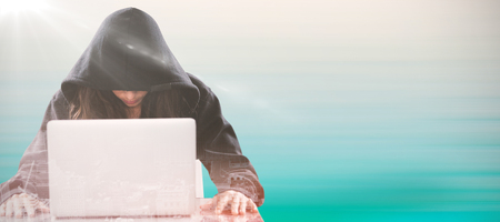 Female hacker sitting by laptop on table  against turquoise abstract backgroundsの写真素材