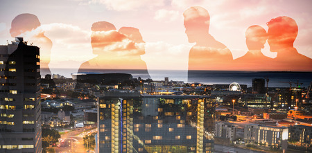 Silhouettes shaking hands against illuminated buildings by road in cityの写真素材